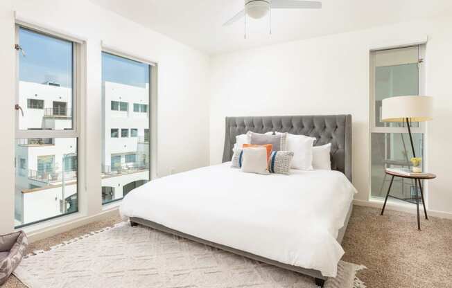 a bedroom with a large bed and three large windows