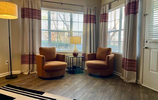 a living room with two chairs and curtains