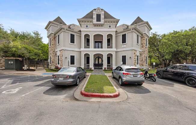 A large house with a driveway and cars parked in front.
