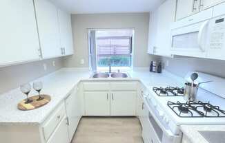 a white kitchen with white cabinets and a window