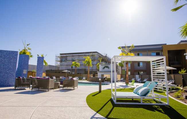 a patio with lounge chairs and a pool at a hotel with palm trees