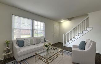 a living room with a white couch and a staircase