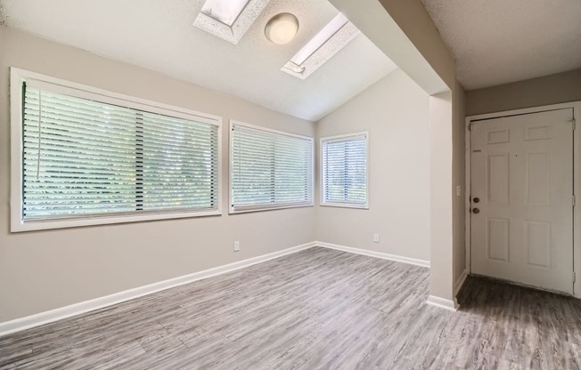 an empty living room with a white door and large windows