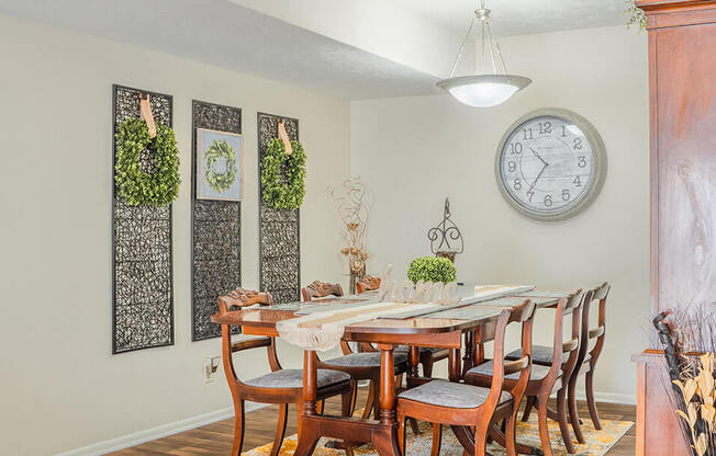 a dining room with a table and chairs and a clock on the wall