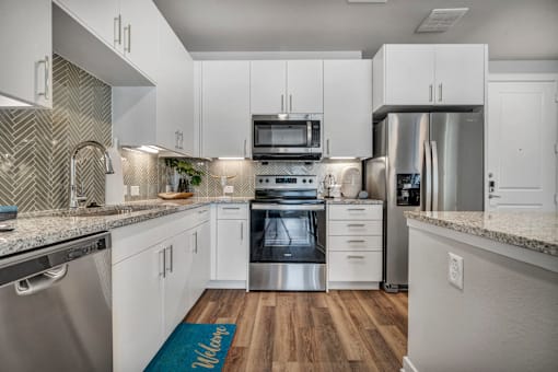 A modern kitchen with white cabinets and stainless steel appliances.