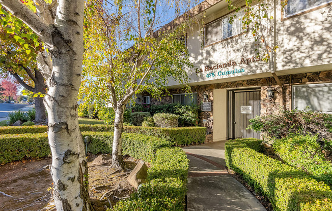 a view of the front of the building with hedges and trees in front of it