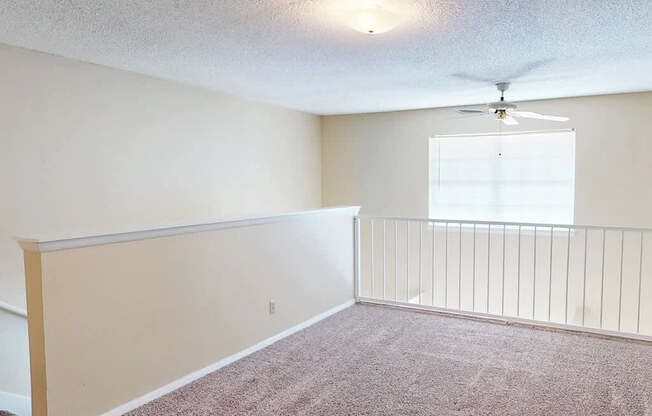 A room with a ceiling fan and a window with blinds.