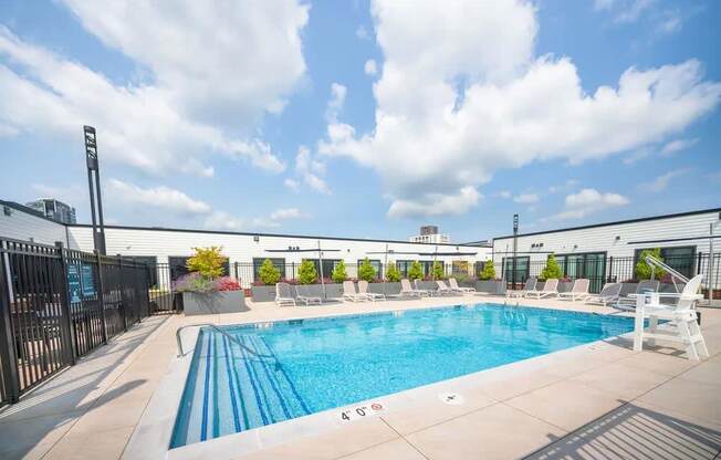 a pool on the roof of a building with chairs around it