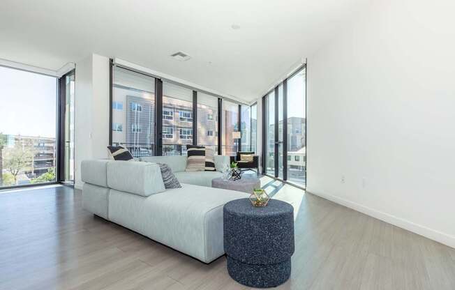 A modern living room with a white sofa and a round ottoman.