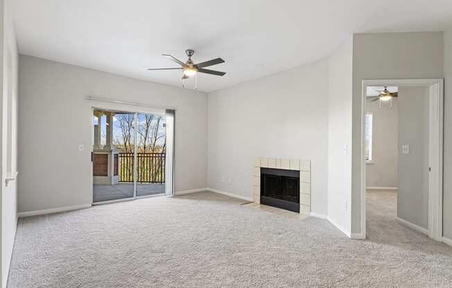 an empty living room with a fireplace and a ceiling fan