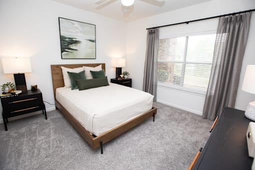 A bedroom with a large bed and two lamps.