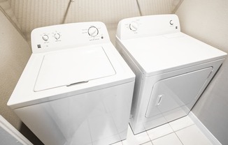 two washers and dryers in a bathroom with white walls