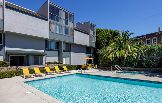 a swimming pool with yellow chairs in front of a building