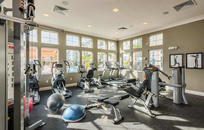 a gym with cardio equipment and windows at the district at highland village apartments