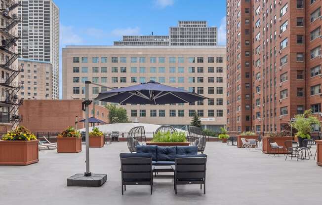 a seating area with couches and chairs on a roof top with a view of the city
