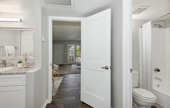 Model Master Bathroom with White Cabinets and Wood-Style Flooring at Stillwater Apartments in Glendale, AZ.