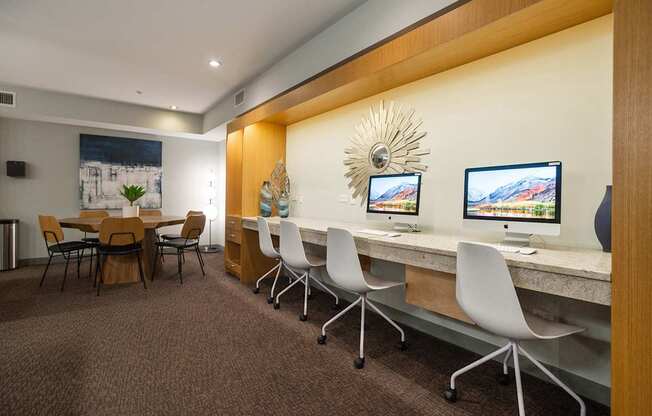 A room with a long table and chairs with computers on it.