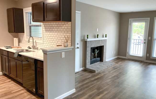 an empty living room with a fireplace and a kitchen