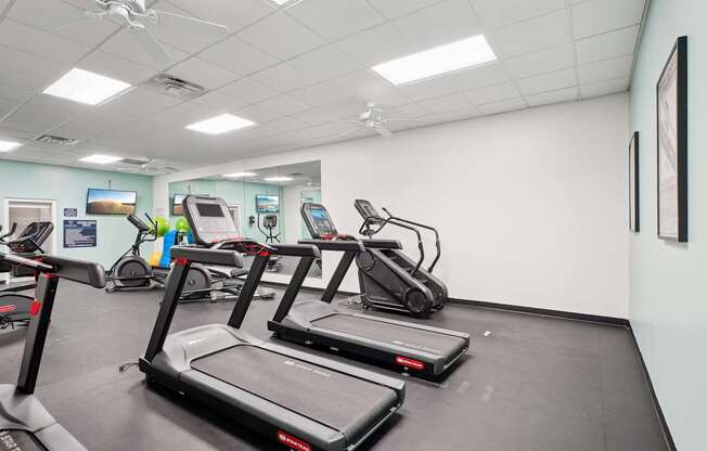 Three treadmills are lined up in a row in a gym.
