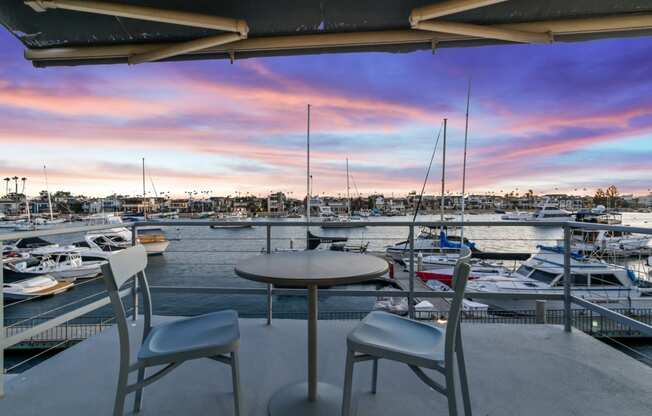 a view of a marina with boats in the water and a patio with chairs