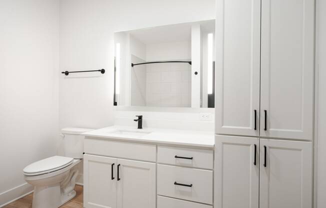 a bathroom with white cabinets and a toilet and a sink