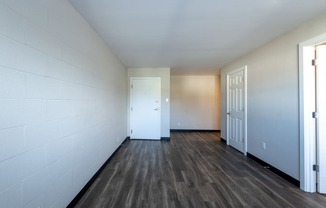 the living room of an empty apartment with wood flooring and a door