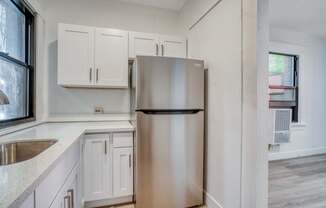 A kitchen with a stainless steel refrigerator and white cabinets.