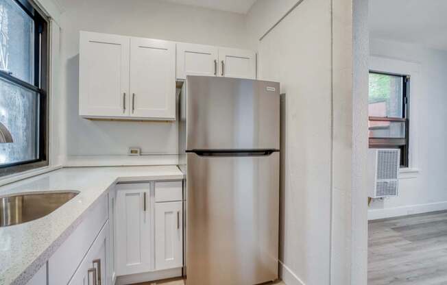 A kitchen with a stainless steel refrigerator and white cabinets.