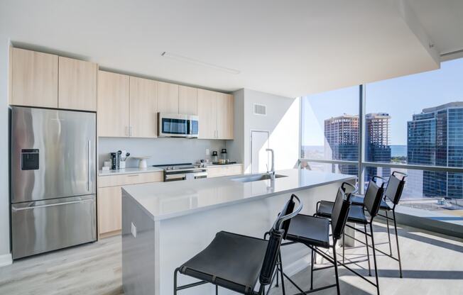 a kitchen with a counter and chairs in front of a window