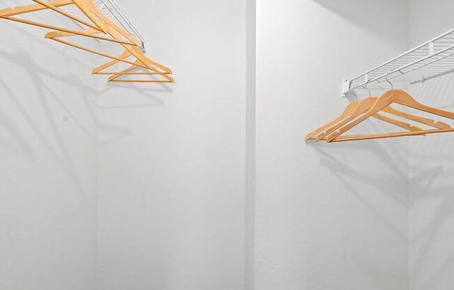 an empty closet with wooden clothes rack on the wall