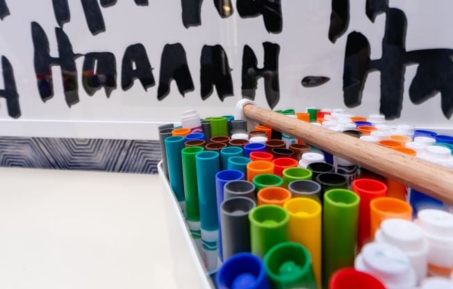 a table full of coloured paints and a wooden stick