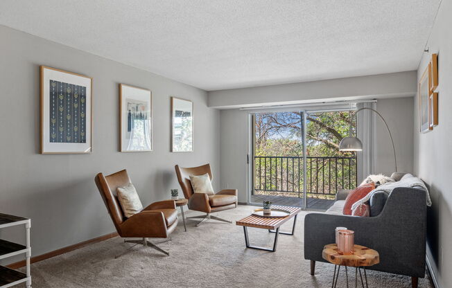 a living room with a couch and chairs and a window