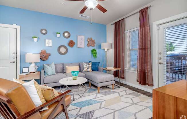 A living room with a blue wall and a ceiling fan.