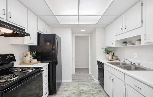 A kitchen with black appliances and white cabinets.