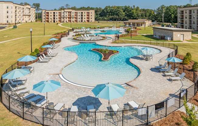 an aerial view of a large swimming pool with umbrellas and chairs around it