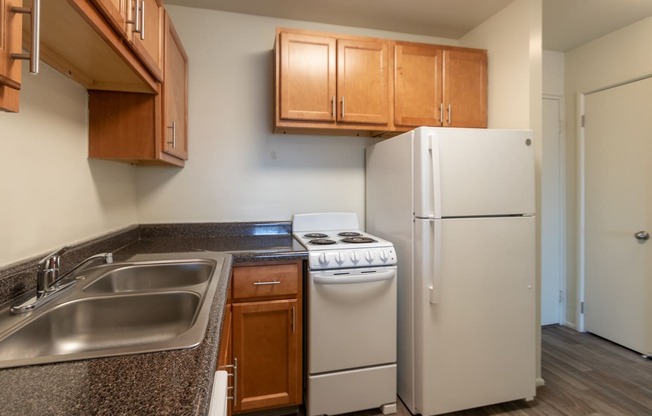 This is a photo of a kitchen with honey oak cabinets and white appliances in a 560 square foot 1, 1 bath apartment at Park Lane Apartments in Cincinnati, OH.