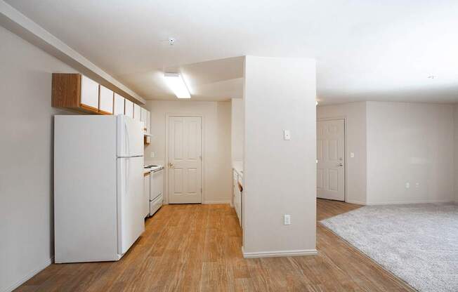 A white refrigerator in a room with wooden floors and white walls.