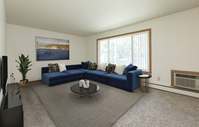 Fargo, ND Islander Apartments. A living room with a large blue couch and a coffee table.  A large window brightens the room with natural light