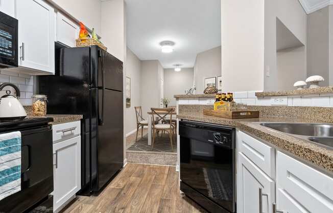 a renovated kitchen with black appliances and white cabinets at Fountains of Denton in Denton Texas