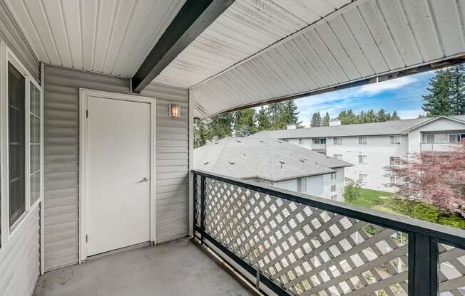 a door leading to a balcony with a white door and a white house in the background