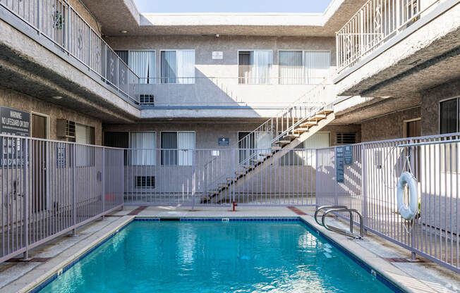A pool in a courtyard surrounded by a metal fence.