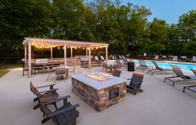 a patio with a fire pit and a pool with chairs and tables