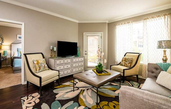 A living room with a sofa, two chairs, a coffee table, and a TV.