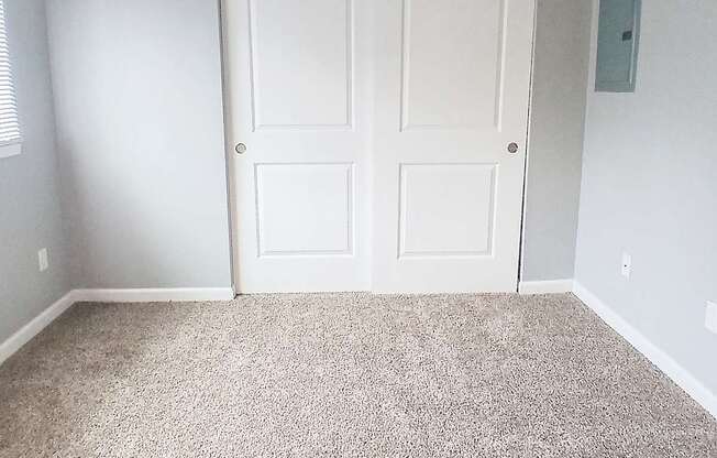 A room with a white door and carpeted floor.