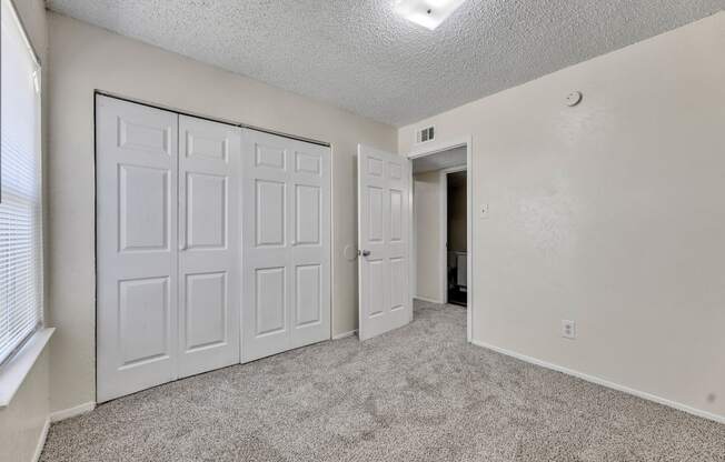 an empty living room with white doors and carpeting