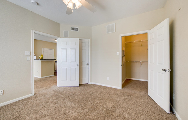 View of Classic Apartment Interior, Showing Bedroom with Ceiling Fan, View of Closet and Kitchen at Stonebriar of Frisco Apartments