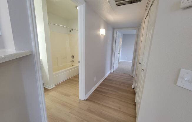 a renovated hallway with wood flooring and white walls