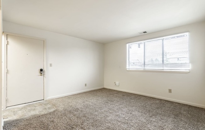 an empty room with carpet and a door and a window at Pheasant Run in Lafayette, IN 47909