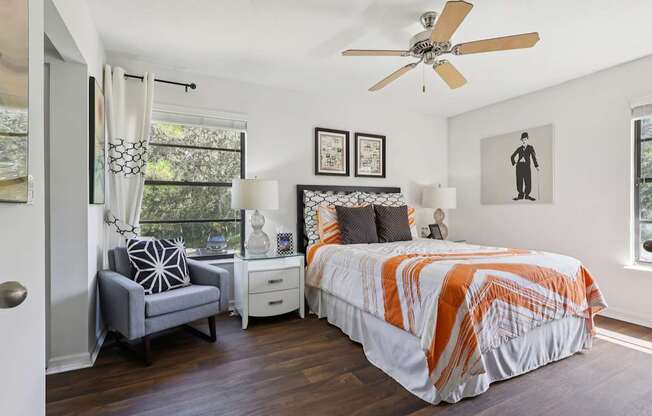 A bedroom with a bed, chair, and pictures on the wall.