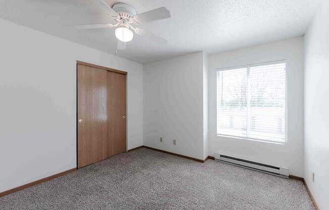 A room with a ceiling fan and a window with blinds.
